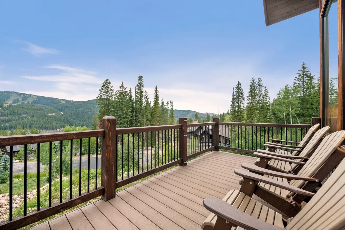 A peaceful wooden deck offers a panoramic view of the mountains and pine trees. The deck provides a serene spot for sunrise yoga, restorative stretches, or simply relaxing and taking in nature’s beauty—reflecting the wellness aspect of the home.